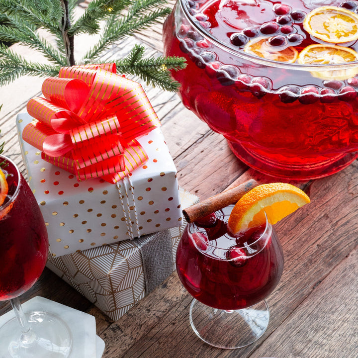 Glass of Merry Maker's Mulled Wine beside presents under a Christmas Tree.