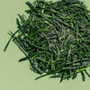 Loose leaf gyokuro green tea to show bright green, flat tea leaves against a green background.