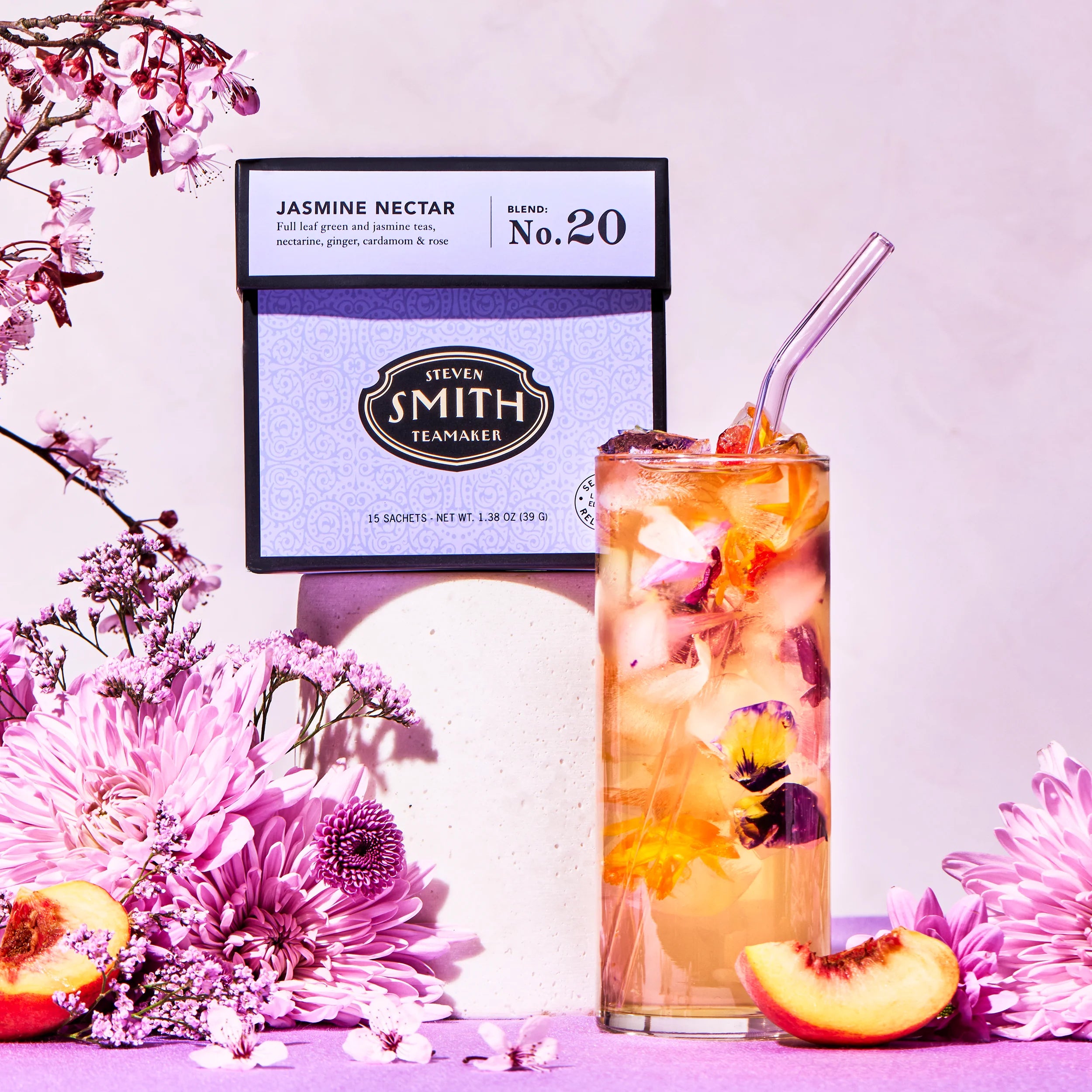 Tea bag labeled 'Jasmine Nectar' with a glass of iced tea and flowers on a pink background