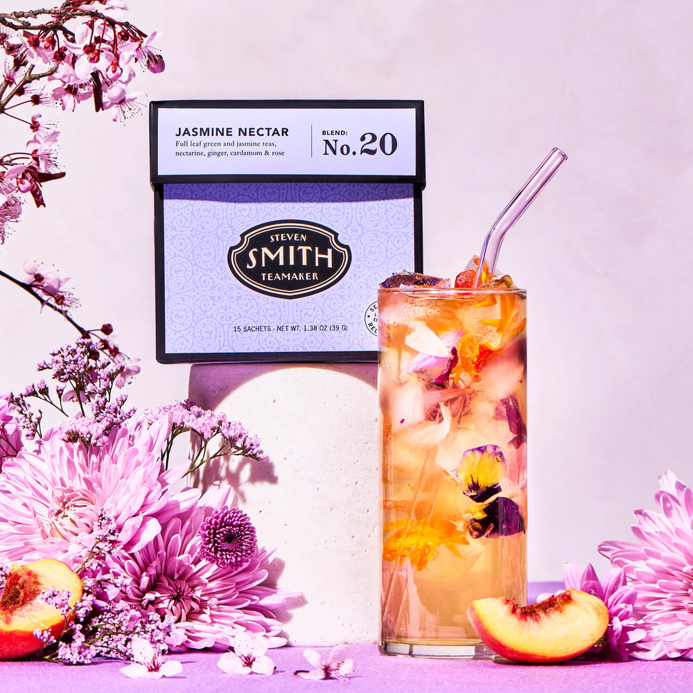 Tea bag labeled 'Jasmine Nectar' with a glass of iced tea and flowers on a pink background