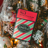 Santa's Little Helper in a festive mini carton with a red top and red and green striped base against a Christmas tree.