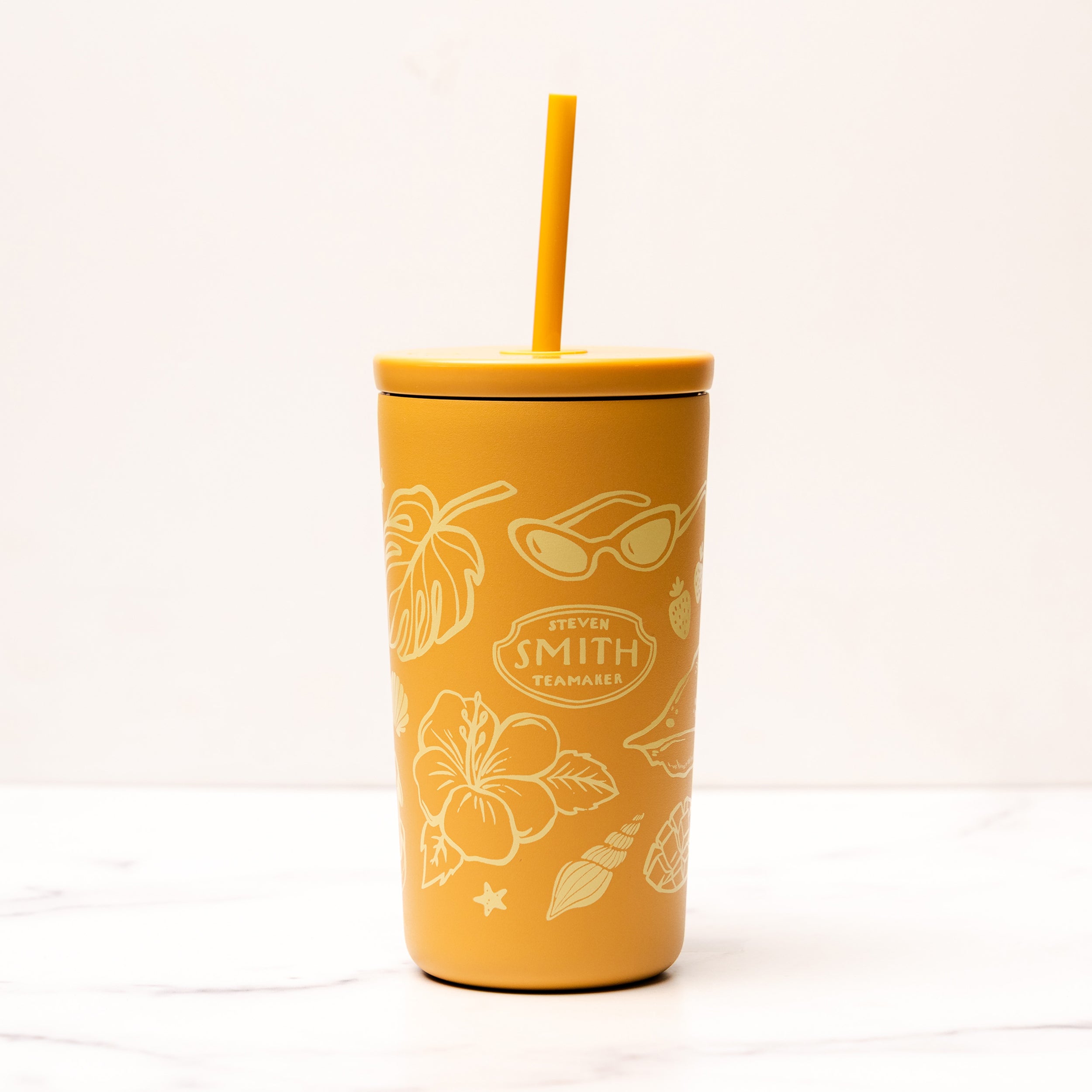 Yellow tumbler with floral and leaf patterns on a white background