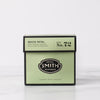 Green box of white petal tea on marble table.