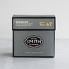 Black carton of tea  on a grey table with a white background.