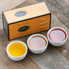 Orange box with black trim on a wooden table with three porcelain cups filled with tea.