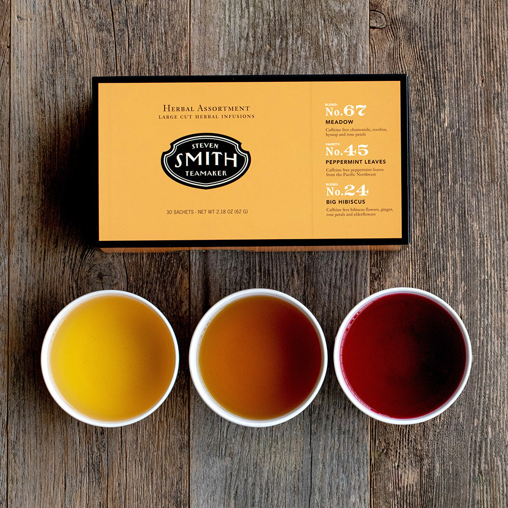 Orange box with black trim on a wooden table with three porcelain cups filled with tea.