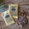 Two gold metallic sachets of tea on wooden background.