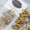 White paper filter with black Smith logo shield filled with chamomile petals.