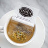 White paper filter with black Smith logo shield filled with chamomile petals.